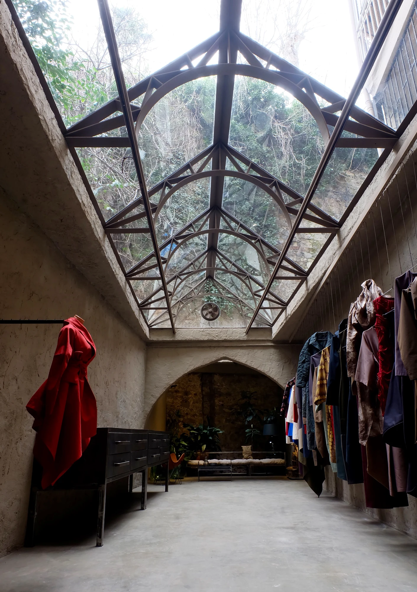 A red garment and textures beneath the atelier’s glass roof